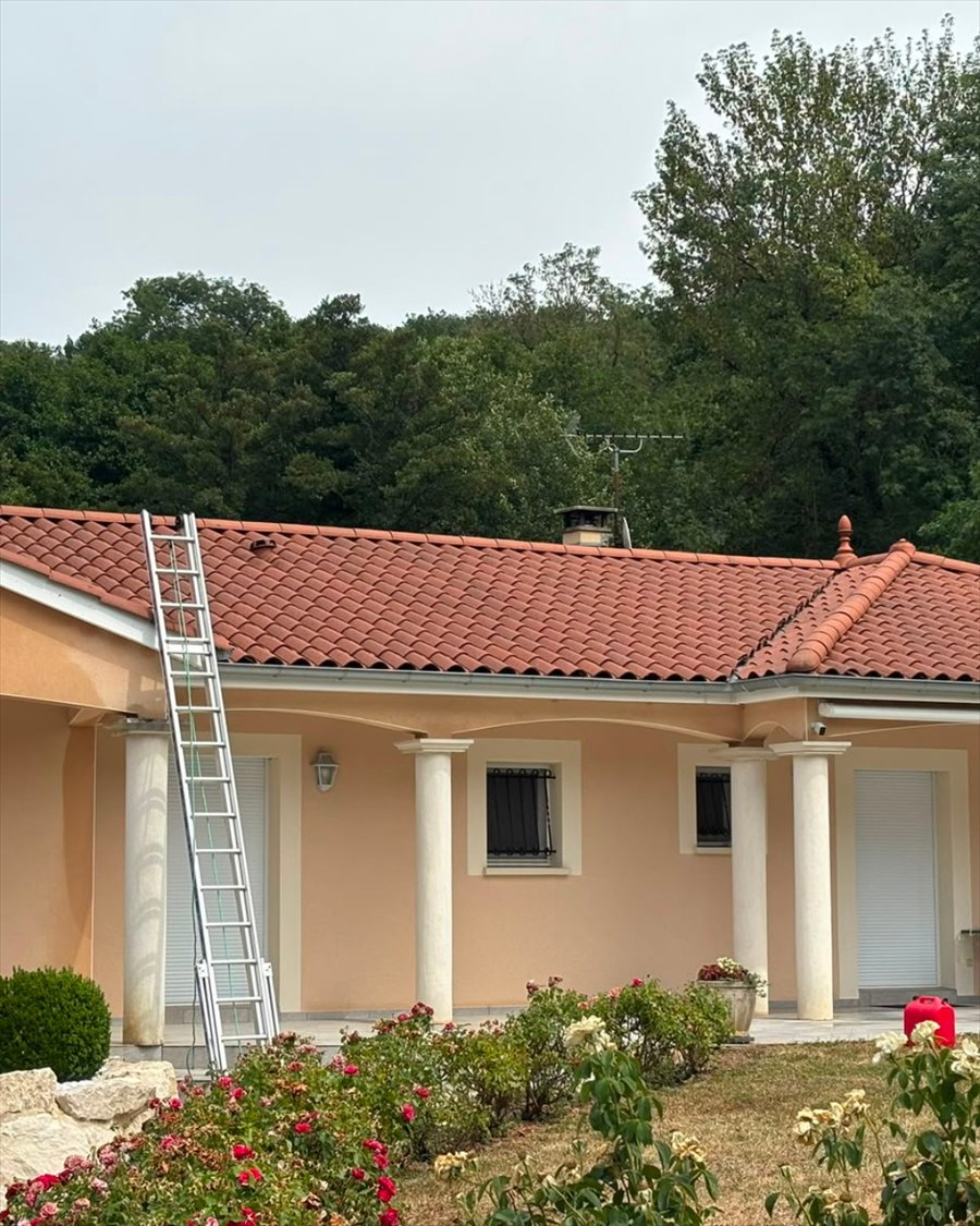 Toiture en tuiles canal rénovée sur une maison de plain-pied, échelle de couvreur en place